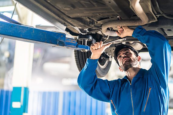 Tire Town Auto Care Center | mechanic working on underside of automobile in the shop